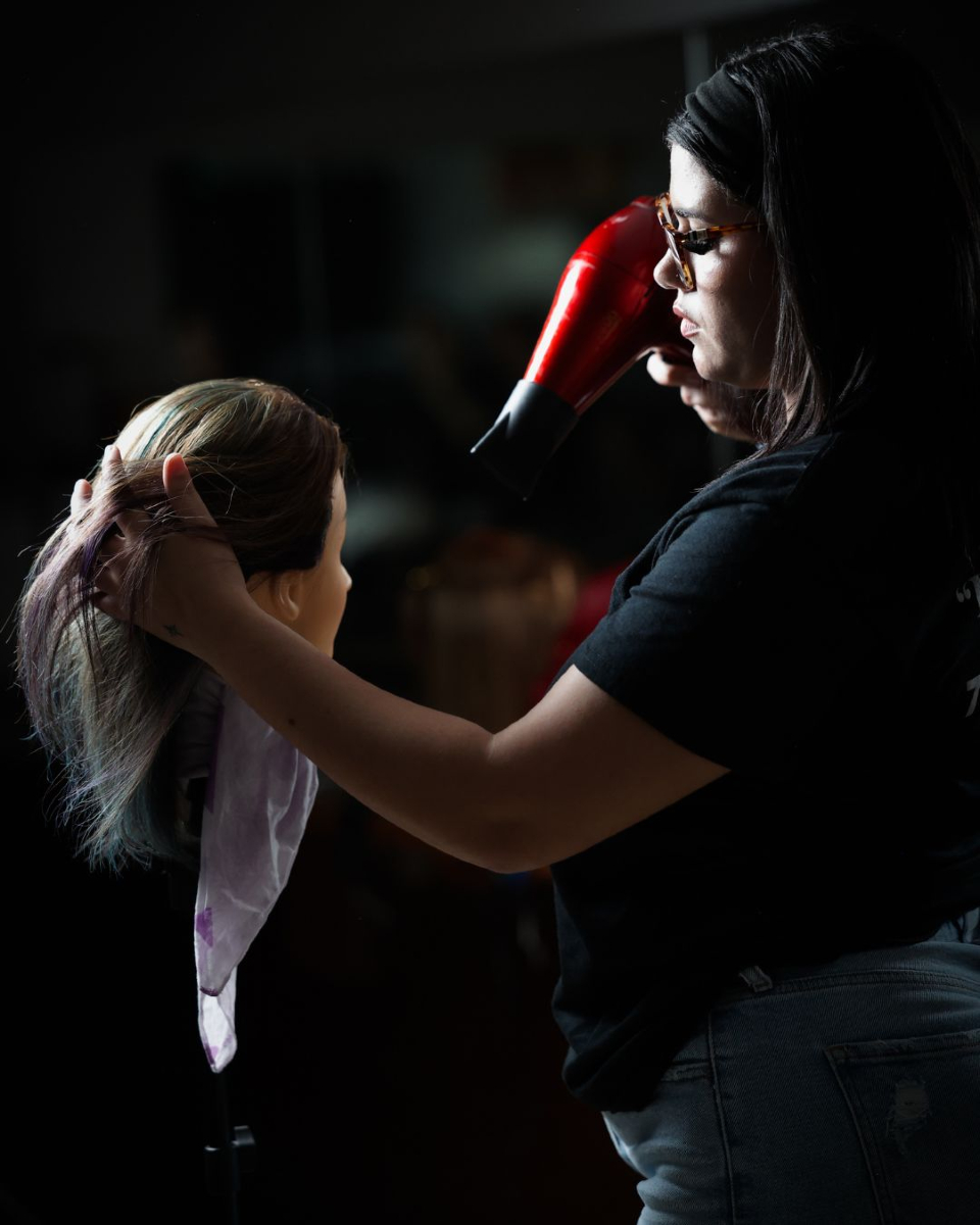 Estudiante de cosmetología secando mechas de color