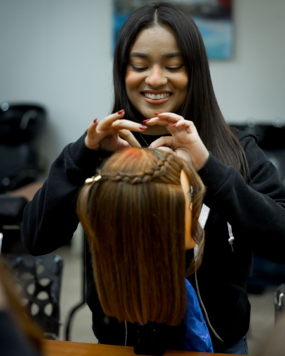 Estudiante de cosmetología realizando una trenza en cabello natural